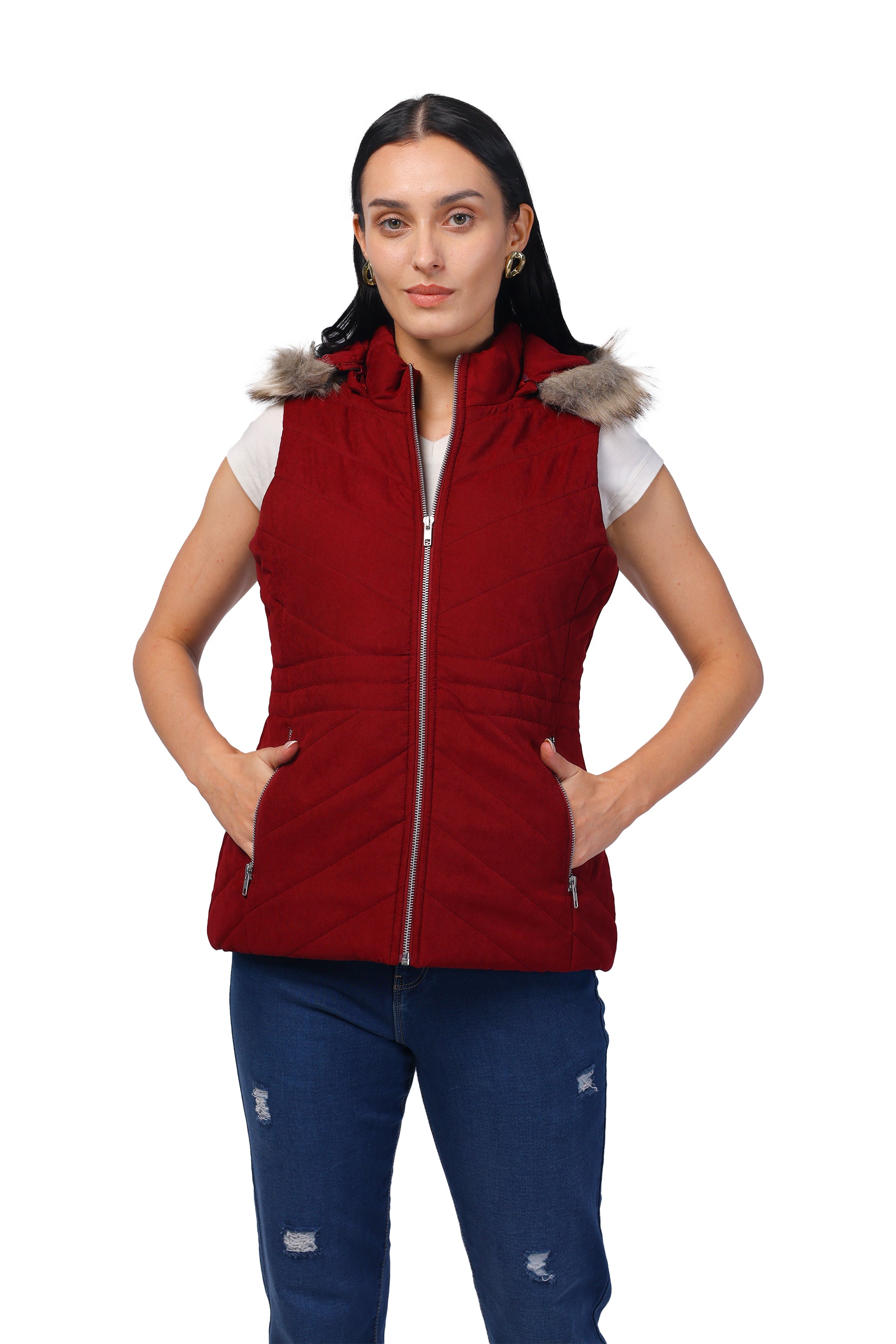 A woman modeling a sleeveless red puffer vest with a gray faux-fur trimmed hood and a front zipper, paired with blue jeans, on a white background.
