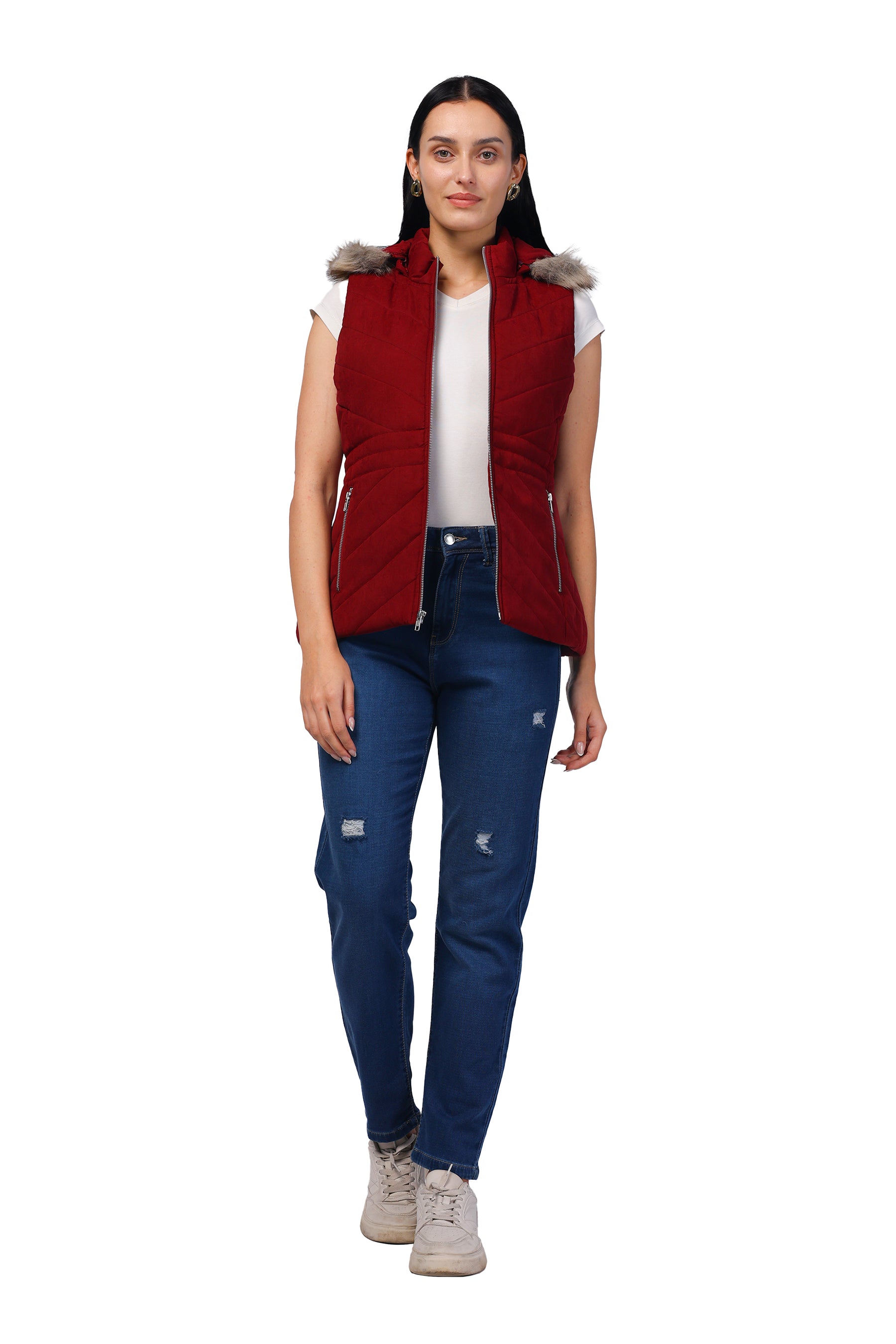 A woman modeling a sleeveless burgundy puffer vest with a faux-fur trimmed hood, worn over a white t-shirt and blue jeans, against a plain white background.