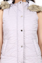 A close-up of a sleeveless quilted puffer vest in a very light lavender or pale lilac color, featuring a faux fur-trimmed hood and front snap buttons.