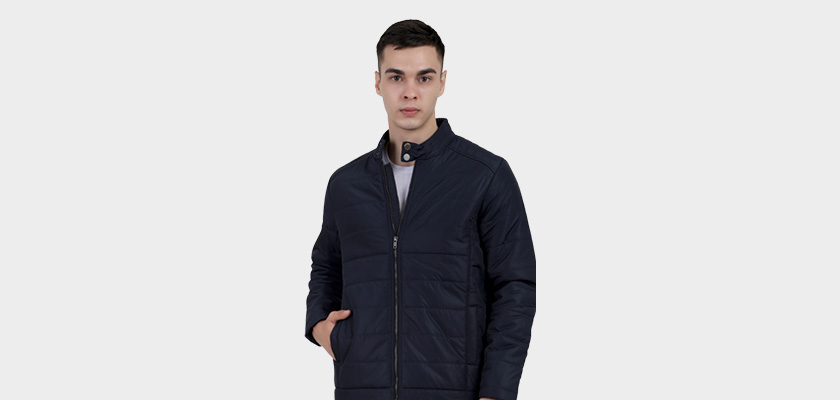 A man wearing a navy quilted biker Jacket with mock collar, zipper closure, and pocket in hand designed for casual winter layering and comfort