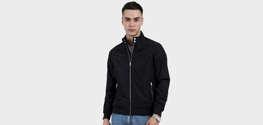 A man wearing a Black Matt Finish Lightweight Jacket with high neck collar, zipper closure and pocket in hand designed for casual winter layering and comfort