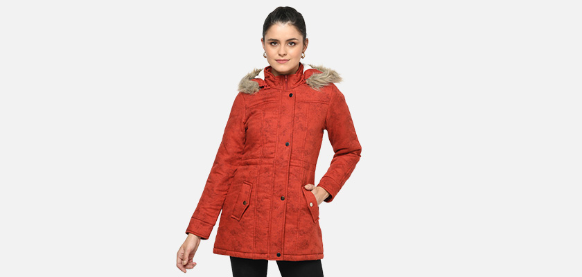 A woman wearing a Red Puffer jacket with a high neck, hood, zipper closure and pocket in hand designed for casual winter layering and comfort