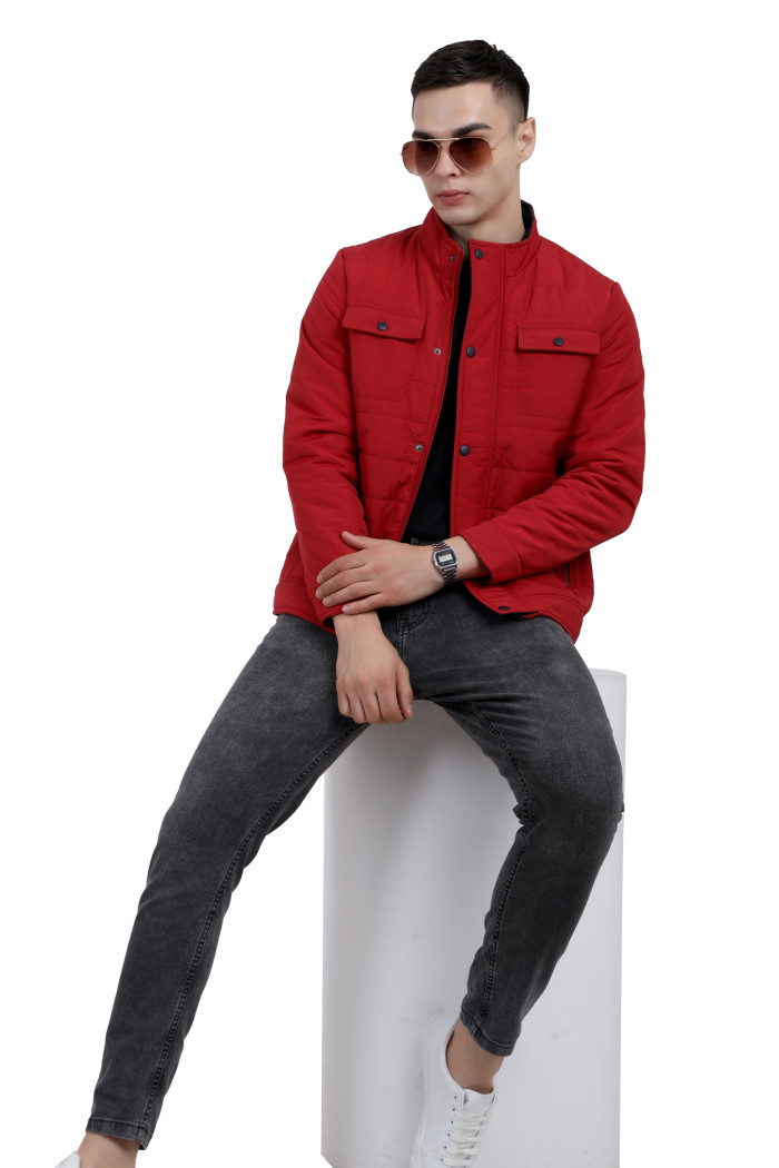 A tilted pose of a Mustard wearing a Red quilted jacket with a high neck collar, zipper closure and pocket in hand designed for casual winter layering and comfort.