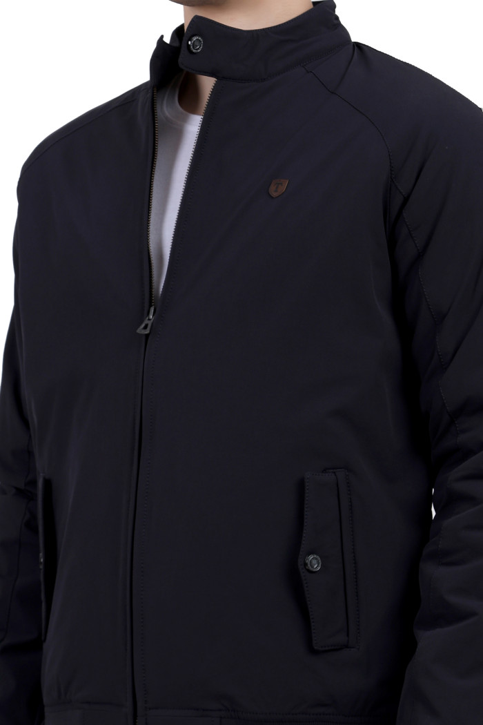 A cropped image of a man wearing a Navy quilted jacket with a high neck collar, zipper closure and pocket in hand designed for casual winter layering and comfort.