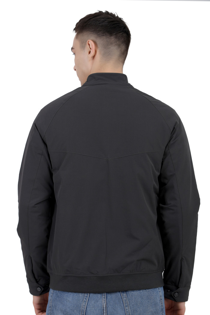 A back pose of a man wearing an olive quilted jacket with a high neck collar, zipper closure and pocket in hand designed for casual winter layering and comfort.