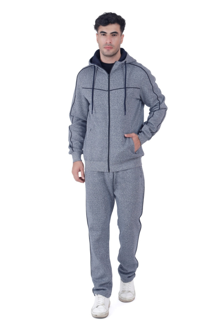 A man wearing a Coatsmore’s navy hooded tracksuit with black piping details and white sneakers, walking confidently against a white background.