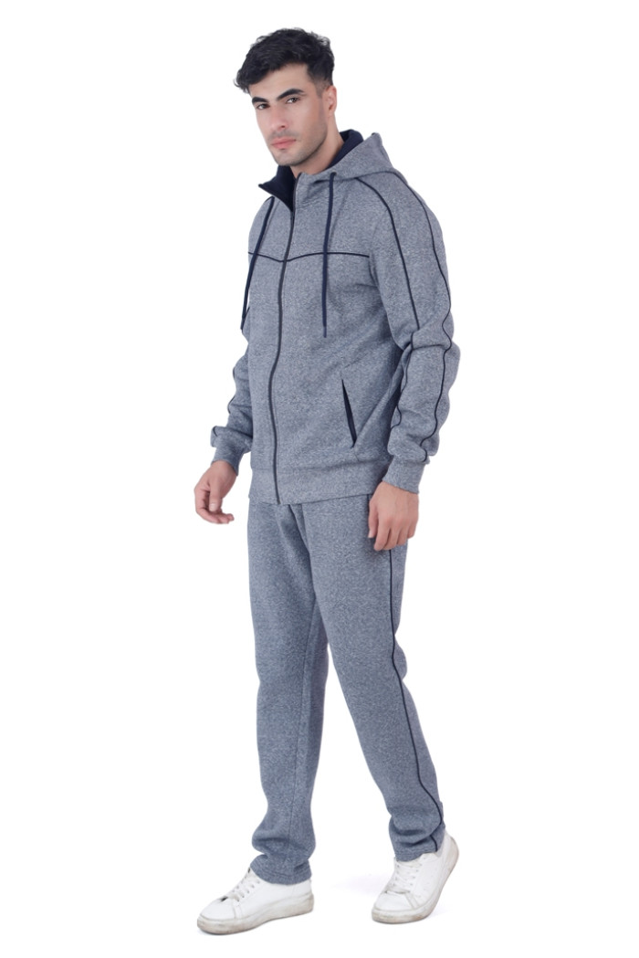 A man dressed in a Coatsmore’s navy hooded tracksuit with black seam accents, standing in a casual pose while facing slightly to the side, wearing white sneakers against a plain white background.