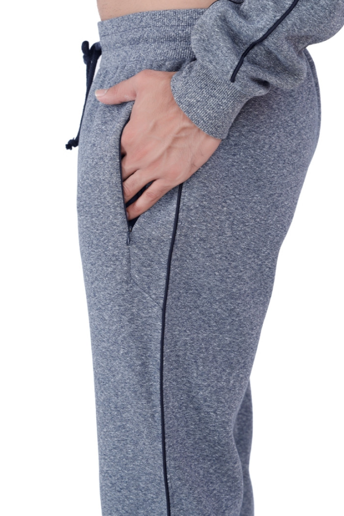 Close-up view of a man's hand in the pocket of Coatsmore’s navy jogger pants featuring black piping and a drawstring waist, showcasing the fabric texture and pocket detail.