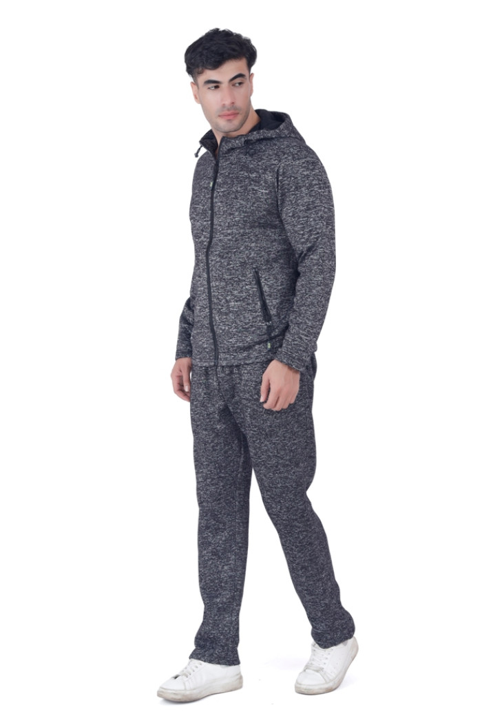 A man in Turfit’s black zip-up hooded tracksuit with zippered pockets, posing sideways in a relaxed stance, wearing white sneakers against a white background.