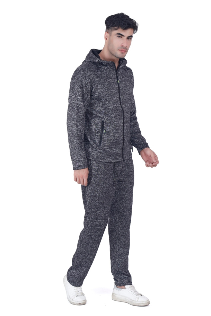 A man wearing Turfit’s black zip-up tracksuit with a hood and zippered pockets, standing in a forward-facing pose with one hand slightly raised, paired with white sneakers against a white background.
