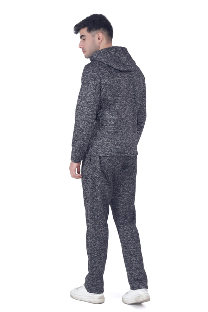 A man wearing Turfit’s black zip-up tracksuit with a hood and zippered pockets, standing in a forward-facing pose with one hand slightly raised, paired with white sneakers against a white background.