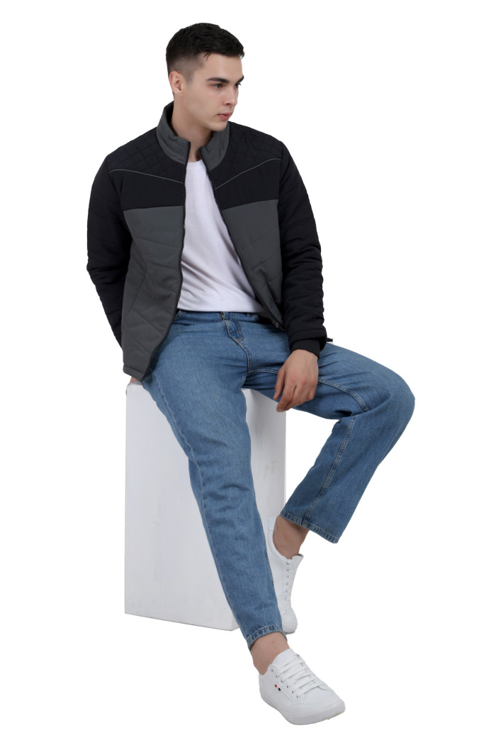 A tilted pose of a man wearing a Black-Grey dual Tone Quilted Jacket with mock collar, zipper closure and pocket in hand designed for casual winter layering and comfort.