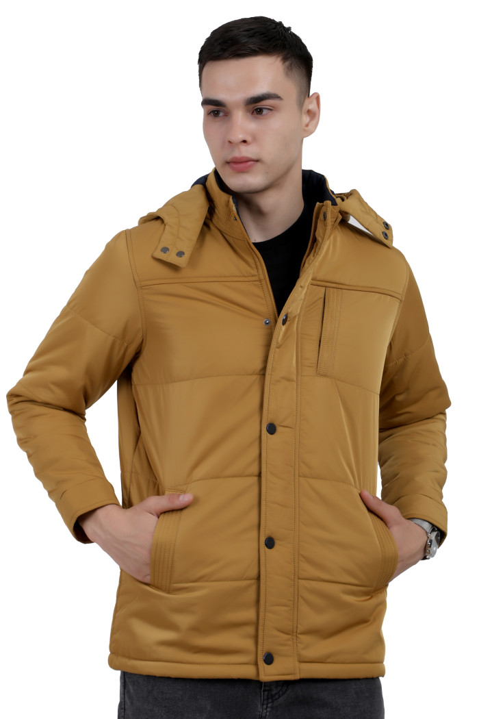 A man wearing a Mustard quilted jacket with a high neck collar, hood , zipper closure and pocket in hand designed for casual winter layering and comfort.