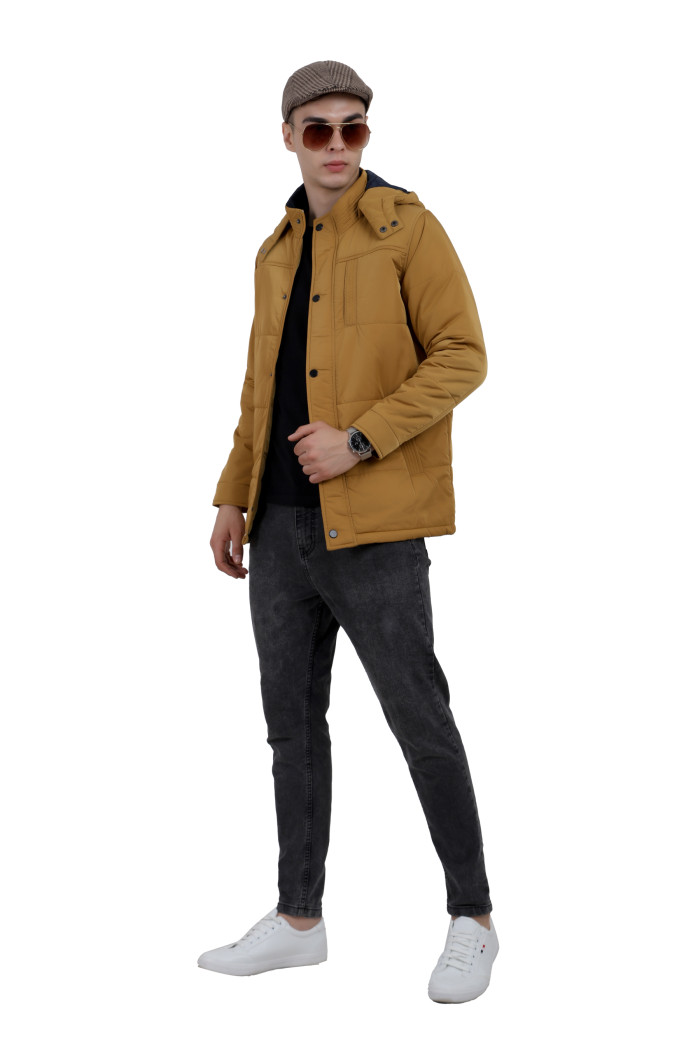 A tilted pose of a Mustard wearing a Red quilted jacket with a high neck collar, hood , zipper closure and pocket in hand designed for casual winter layering and comfort.