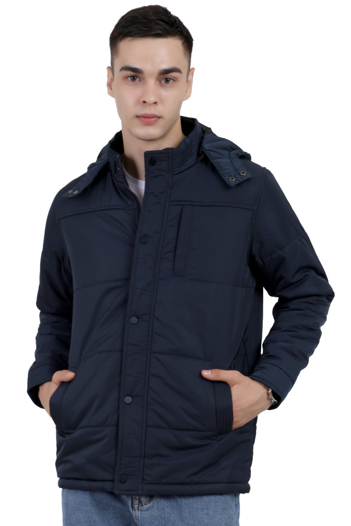 A man wearing a Navy quilted jacket with a high neck collar, hood , zipper closure and pocket in hand designed for casual winter layering and comfort.