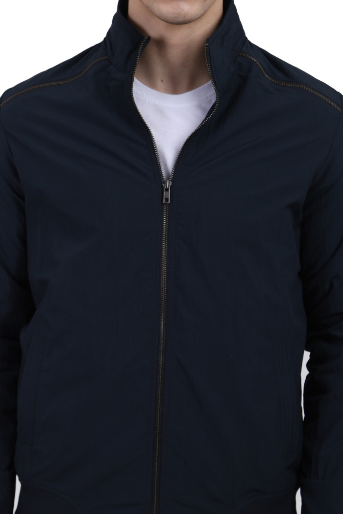 A cropped image of a man wearing Navy riding jacket with a high collar neck, zipper closure and pocket in hand designed for casual winter layering and comfort.