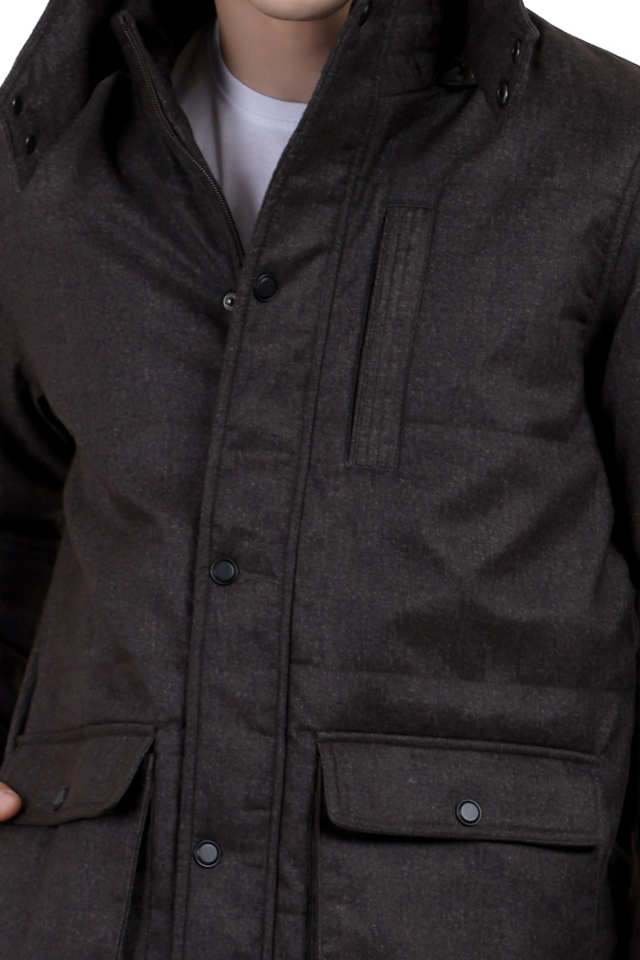 A cropped image of a man wearing a brown Chester jacket with a high neck collar, hood, zipper closure, and pocket in hand designed for casual winter layering and comfort.