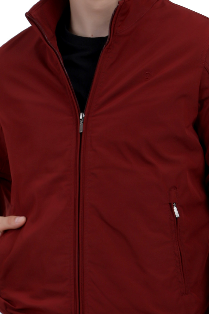 A cropped image of a man wearing a Maroon polyester jacket with a collar neck, zipper closure and pocket in hand designed for casual winter layering and comfort.