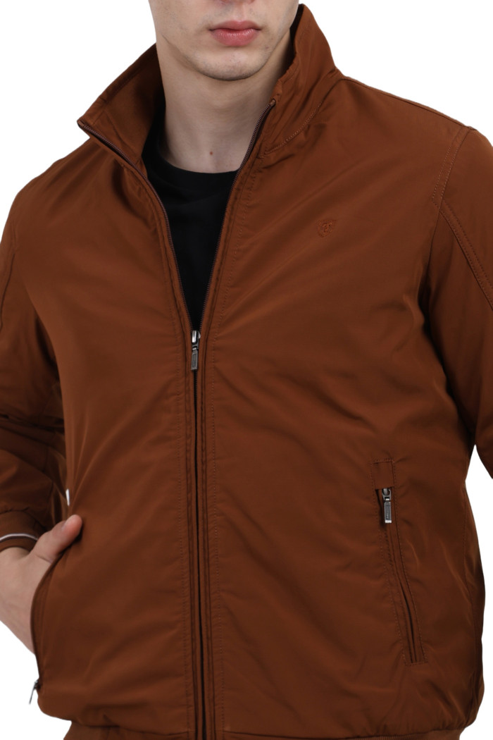 A cropped image of a man wearing a Rust polyester jacket with a collar neck, zipper closure and pocket in hand designed for casual winter layering and comfort.