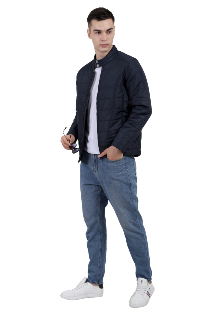 A tilted pose of a man wearing a navy quilted biker Jacket with mock collar, zipper closure and pocket in hand designed for casual winter layering and comfort.