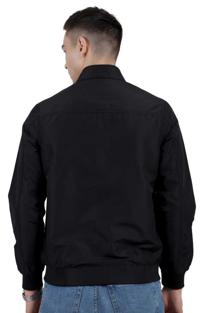 A back pose of a man wearing a Black Matt Finish Lightweight Jacket with high neck collar, zipper closure and pocket in hand designed for casual winter layering and comfort.