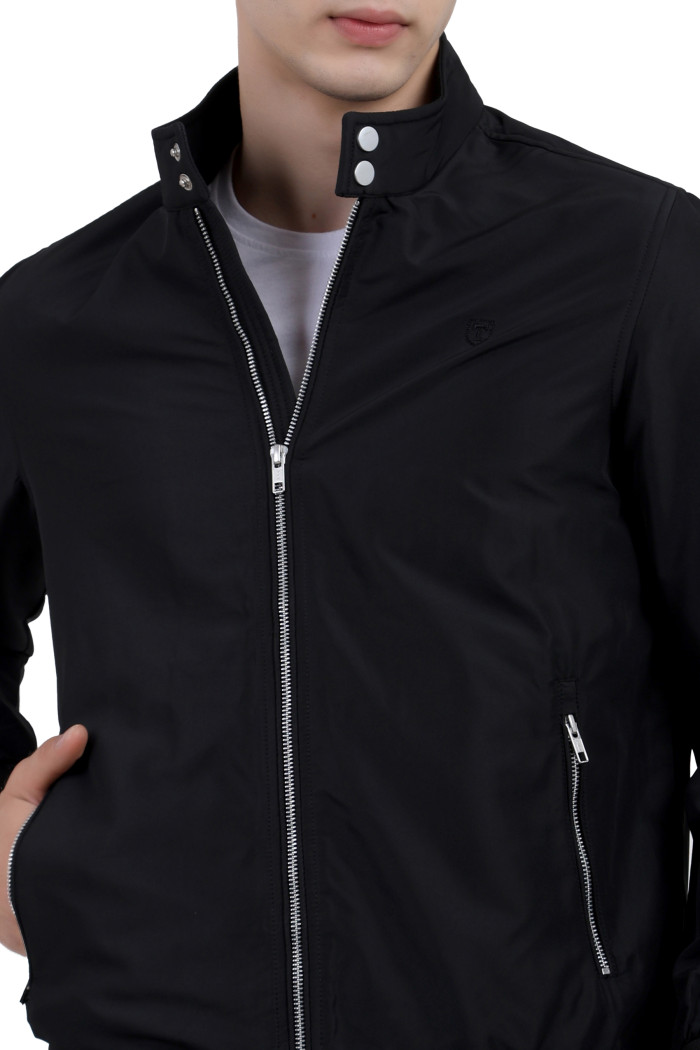 A cropped image of a man wearing a Black Matt Finish Lightweight Jacket with high neck collar, zipper closure, and pocket in hand designed for casual winter layering and comfort.