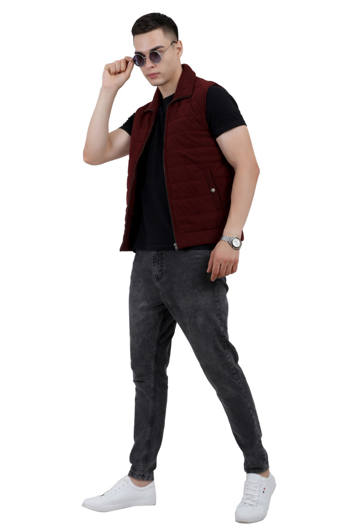 A tilted pose of a man wearing a Maroon half jacket with a high neck, zipper closure and pocket in hand designed for casual winter layering and comfort.