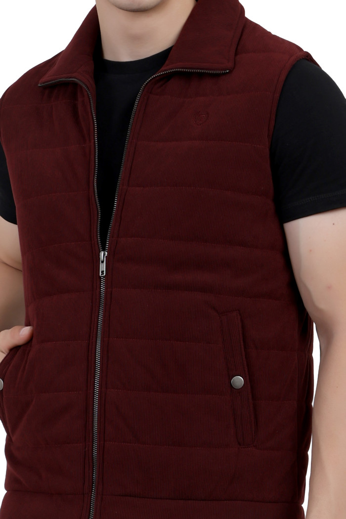 A cropped image of a woman wearing a a Maroon half jacket with a high neck ,zipper closure and pocket designed for casual winter layering and comfort.