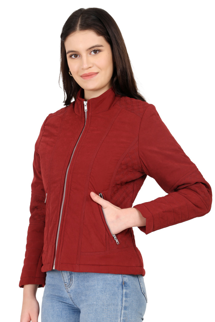 A woman in a standing pose with her one hand in a pocket, wearing Trufit’s maroon quilted biker jacket with a Chinese collar, sliver zip closure, and side pockets with a silver zipper and blue jeans.