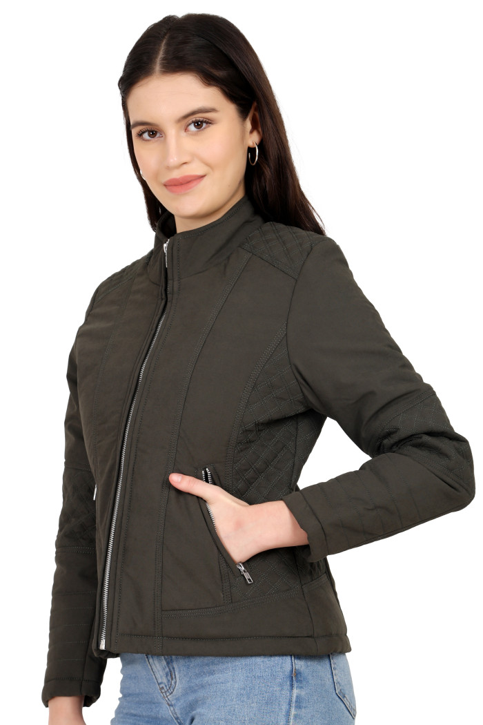 A woman in a standing side pose with her one hand in a pocket, wearing Trufit’s black quilted biker jacket with a Chinese collar, sliver zip closure, and side pockets with a silver zipper and blue jeans.