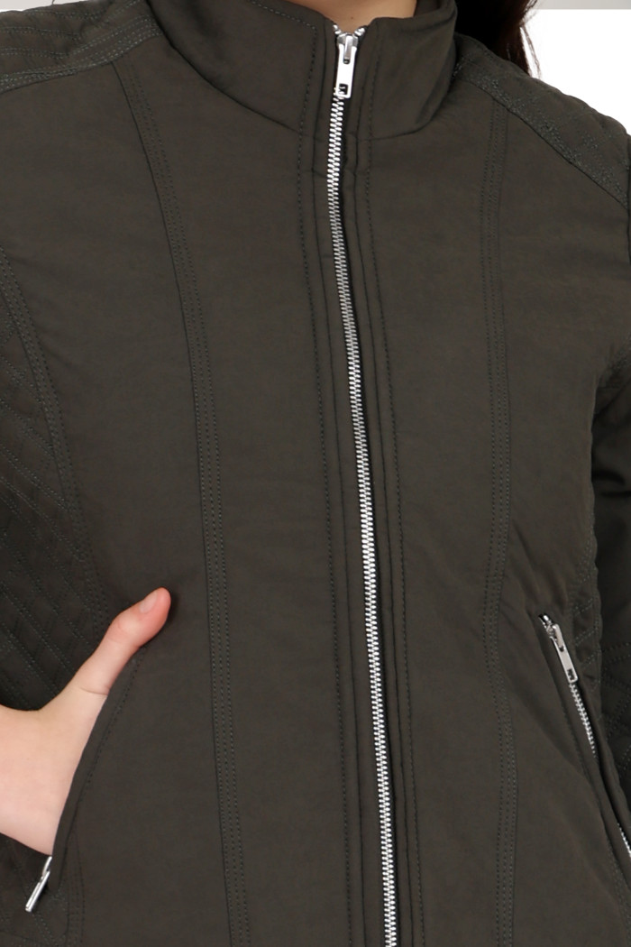 A cropped image of a woman wearing Trufit’s olive quilted biker jacket with a Chinese collar, sliver zip closure and side pockets with a silver zipper.