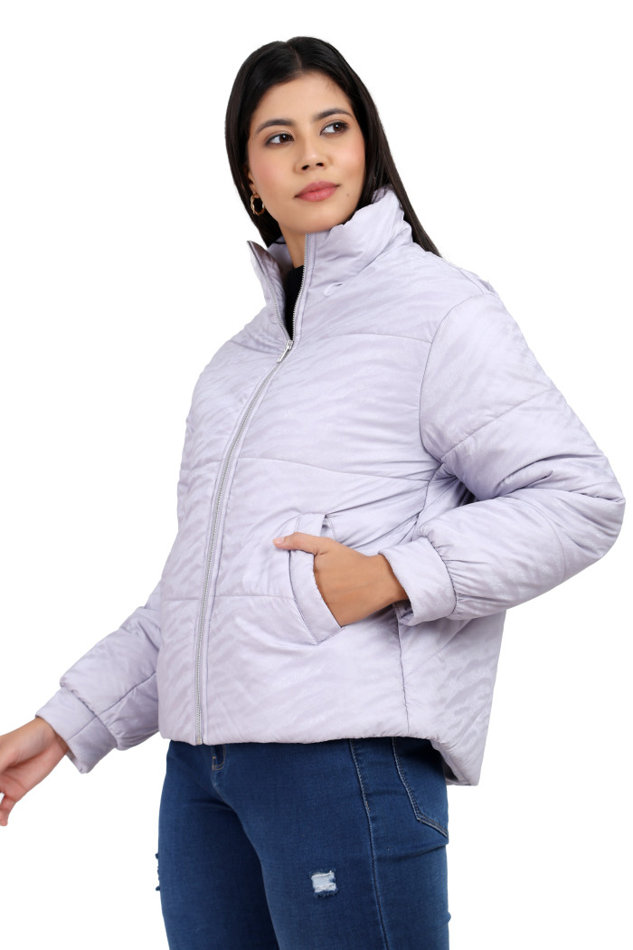 A woman in a standing side pose, wearing Trufit’s mauve quilted jacket with a high neck collar, zip closure, side pockets and blue jeans with her left hand in the pocket.