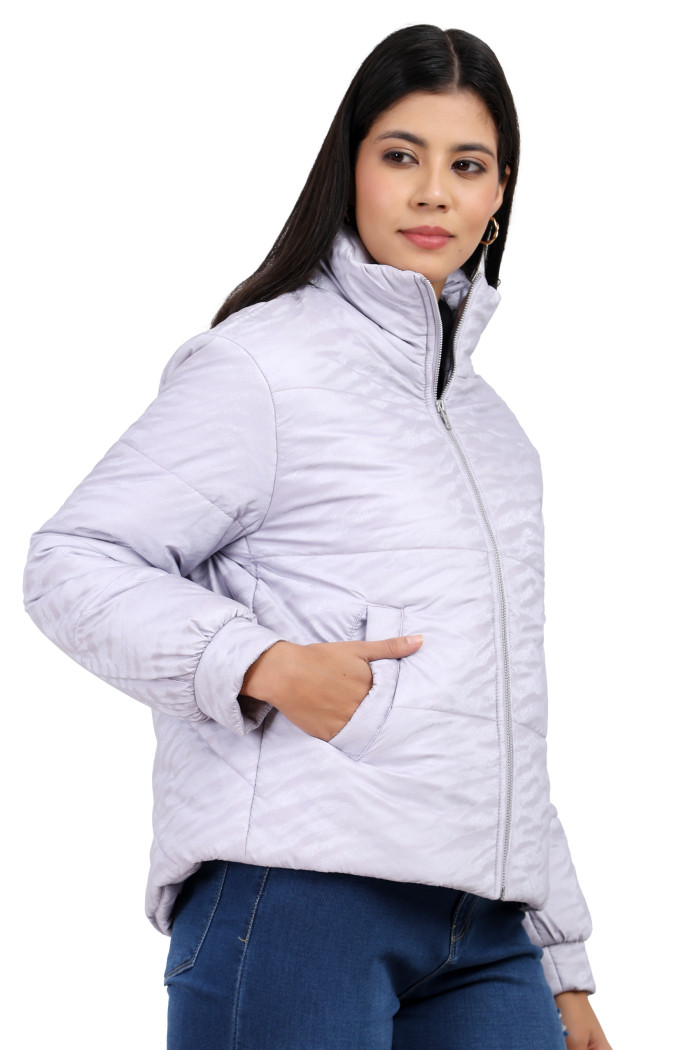 A woman in a standing side pose, wearing Trufit’s mauve quilted jacket with a high neck collar, zip closure, side pockets and blue jeans with her right hand in pocket.