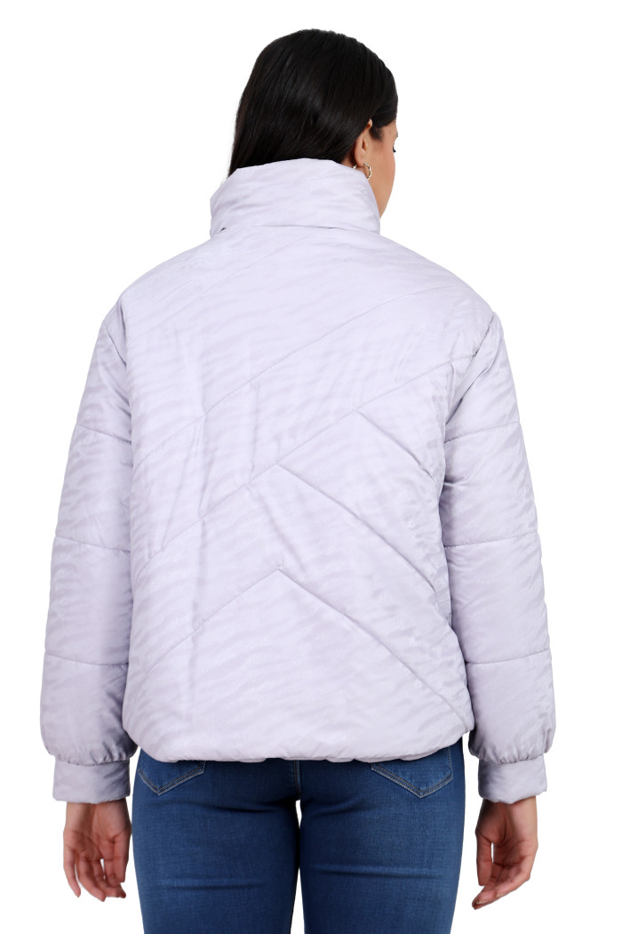 A back pose of a standing woman, wearing Trufit’s mauve quilted jacket and blue jeans.