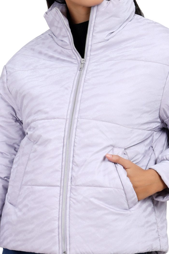 A cropped image of a woman wearing Trufit’s mauve quilted jacket with a high neck, zip closure, with one hand in her side pockets.