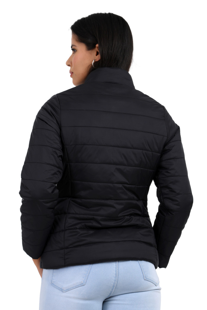 The back view of a standing woman displays Coatsnmore’s black quilted jacket paired effortlessly with blue jeans.