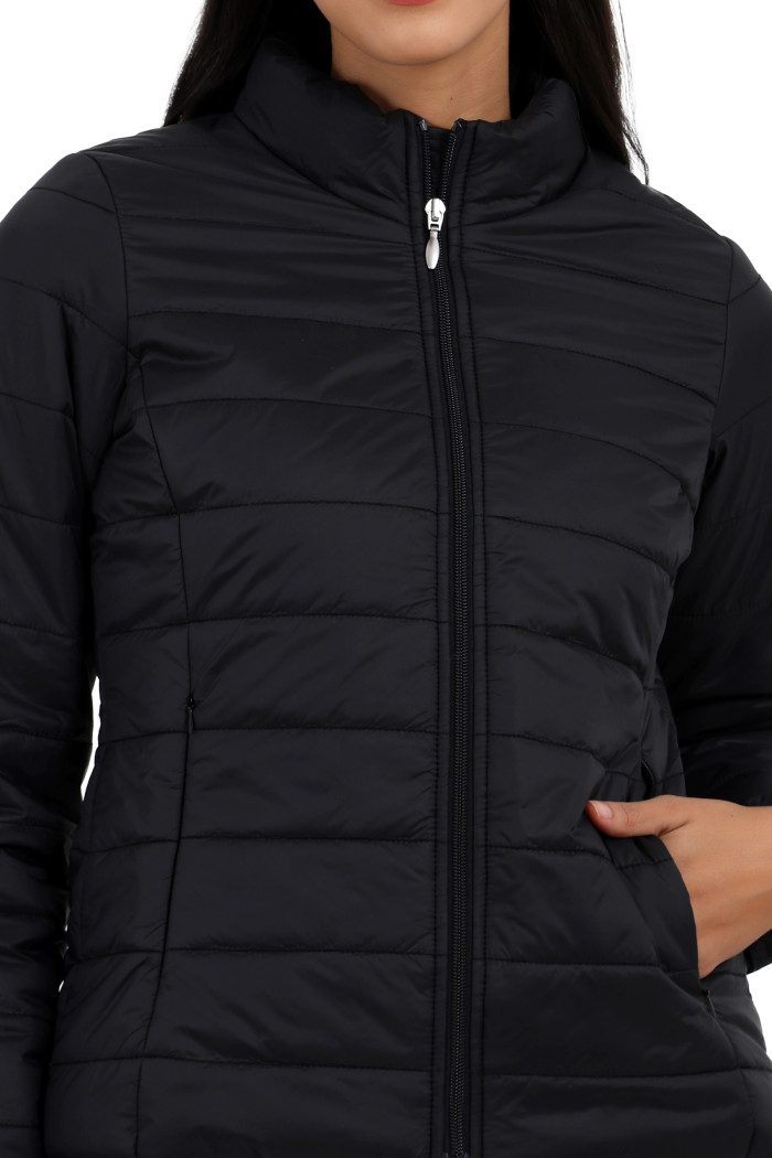 A cropped view of a woman in Coatsnmore’s black quilted jacket, featuring a high neck collar, zip closure, and concealed zippered side pockets, with her right hand in the pocket.