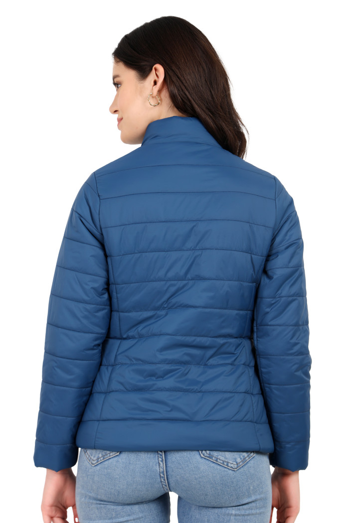 The back view of a standing woman displays Coatsnmore’s blue quilted jacket paired effortlessly with blue jeans.