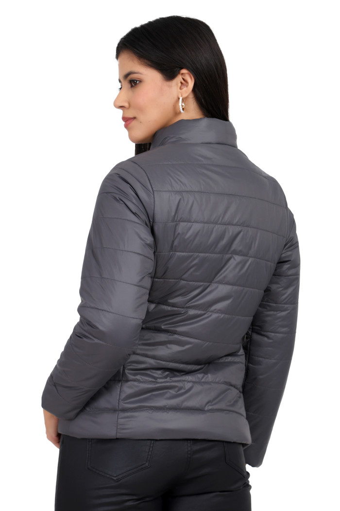 A back pose of a standing woman, wearing Coatsnmore’s grey quilted jacket and black jeans.