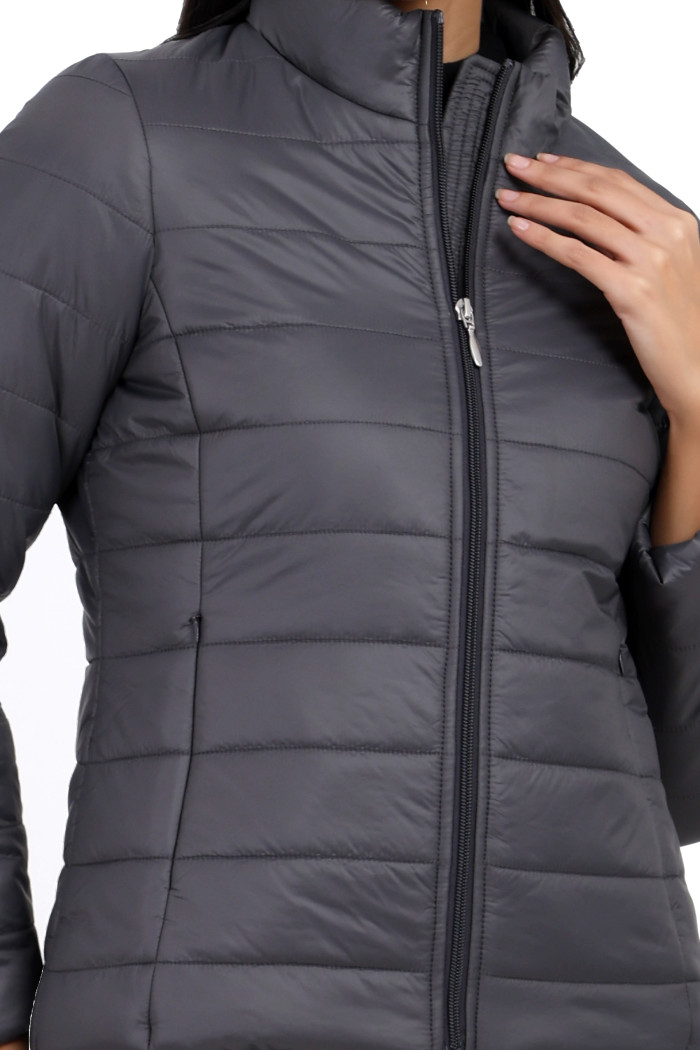 A cropped image of a woman wearing Coatsnmore’s grey quilted jacket with a high neck, zip closure and concealed zipper while touching her collar with her left hand.