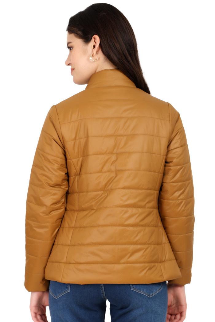 A back pose of a standing woman, wearing Coatsnmore’s tan quilted jacket and blue jeans.