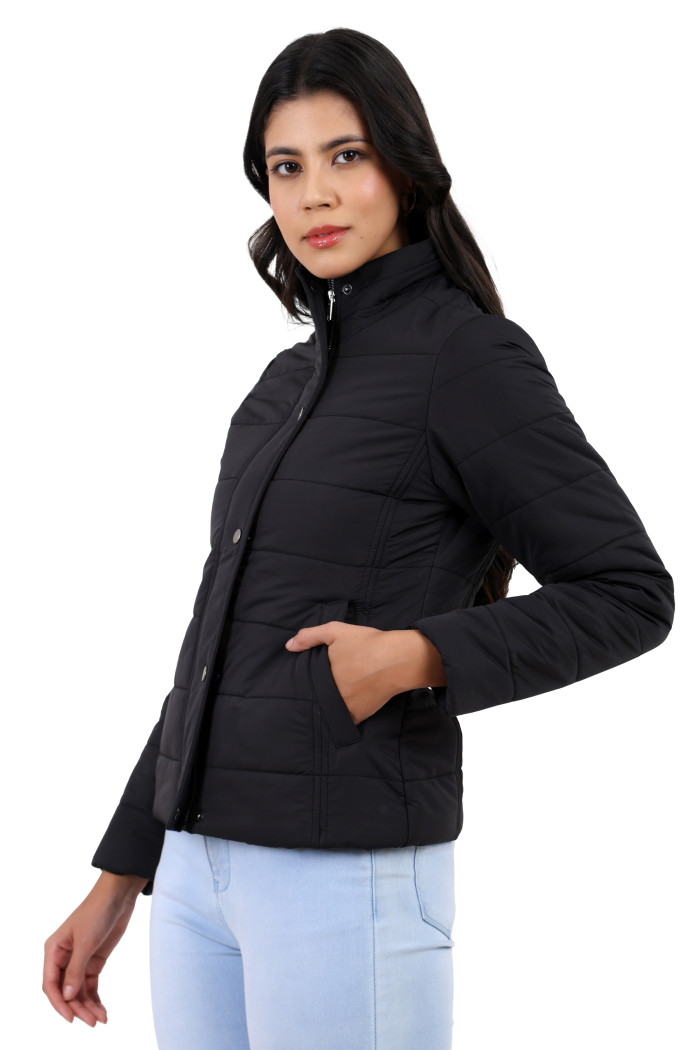 A woman in a standing side pose is wearing Trufit’s olive quilted jacket with a high neck collar, zip closure, button plackets, side pockets, and blue jeans while her left hand is in the pocket.