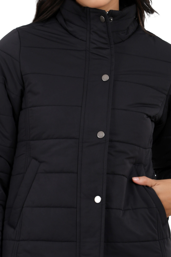 A cropped image of a woman wearing Trufit’s olive quilted jacket without a hood with a high neck, zip closure, button placket, and side pockets.