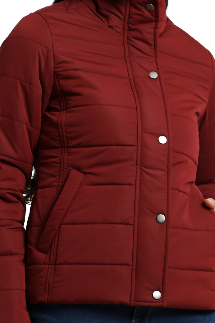 A cropped frame captures a woman dressed in Coatsnmore’s navy quilted jacket, featuring a high neck collar, zip-up design, concealed zippers on the side pockets, and her left hand in the pocket.