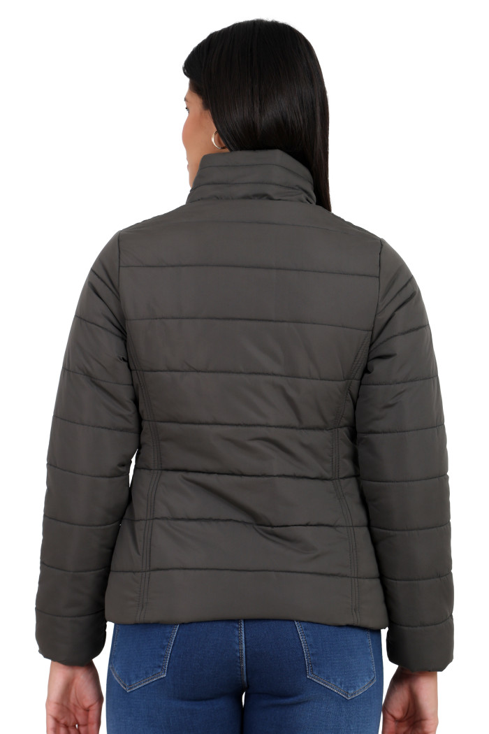 A back pose of a standing woman, wearing Trufit’s olive quilted jacket without a hood and blue jeans.