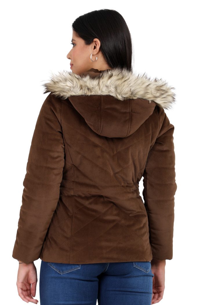 A back pose of a standing woman, wearing Coatsnmore’s coffee velvet quilted jacket with a removable hood and blue jeans.