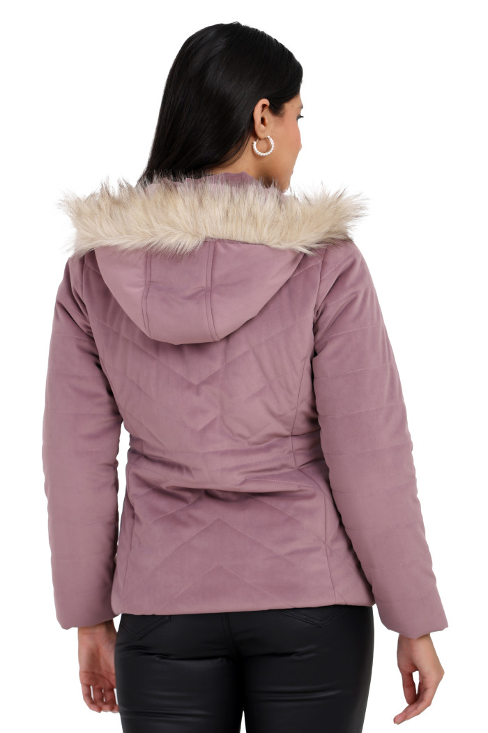 A back pose of a standing woman, wearing Coatsnmore’s lilace velvet quilted jacket with a removable hood and black jeans.