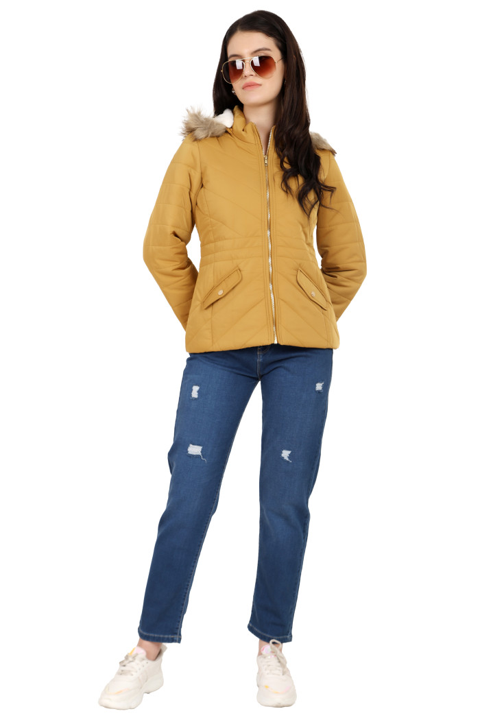 A woman is giving a standing pose wearing black shades, coatsnmore’s casual jacket in mustard colour with a textured pattern, slash placket pockets, a zip closure, a detachable hood and blue jeans with her hands back.