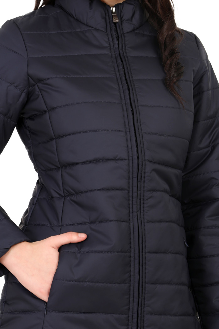 A cropped image of a woman wearing Coatsnmore’s navy quilted jacket with a mandarin collar, zip closure and side pockets with concealed zippers, and her right hand is in the pocket.