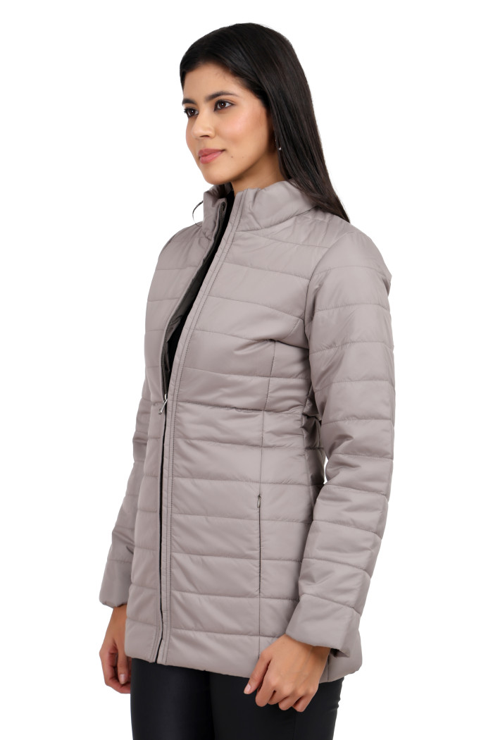 A woman in a standing side pose is wearing Trufit’s stone quilted jacket with a mandarin collar, zip closure, side pockets with concealed zippers, and black jeans.